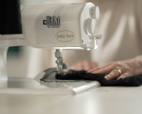 A woman sewing a black fabric with a 