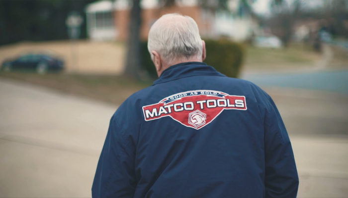 A man wearing blue Matco Tools jacket with a red logo.